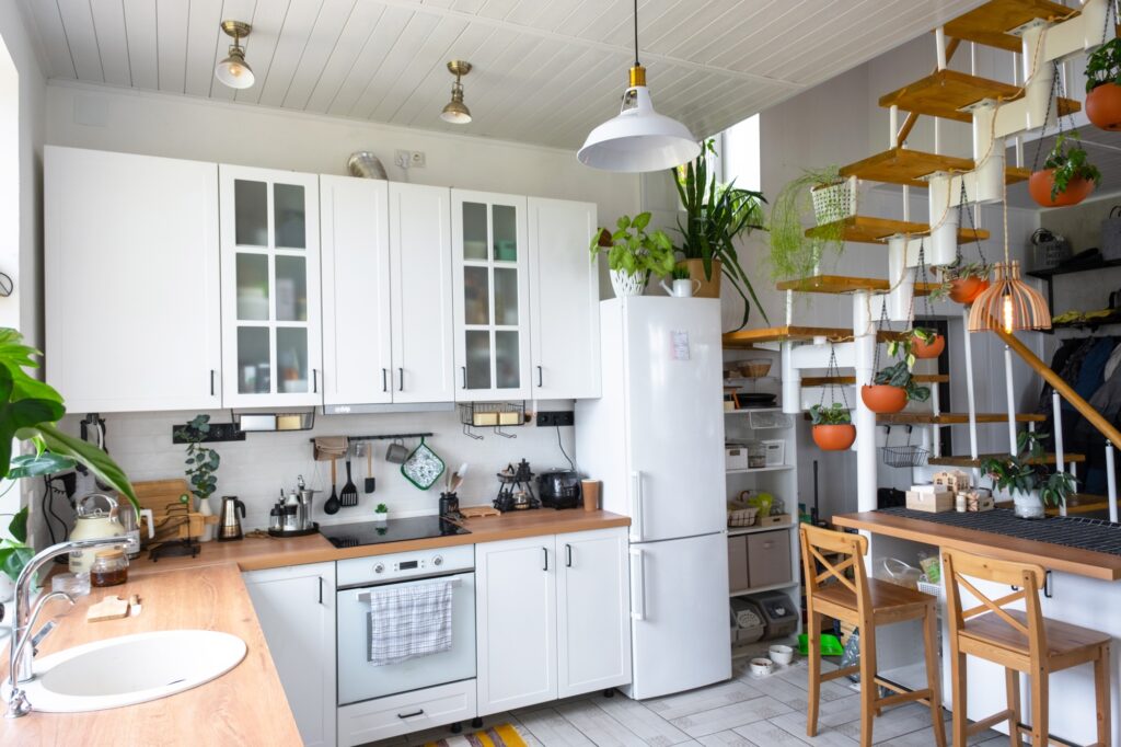The general plan of a light white modern rustic kitchen with a modular metal staircase decorated wit